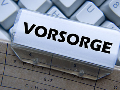 Ein Dokumentenhalter mit dem Wort "VORSORGE" und einem verschwommenen Hintergrund einer Tastatur.
